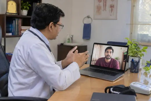 Connecting a doctor and patient for an online consultation Doctor speaking with a patient by video call from his chamber